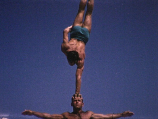A man holds himself up by one arm above another man. 